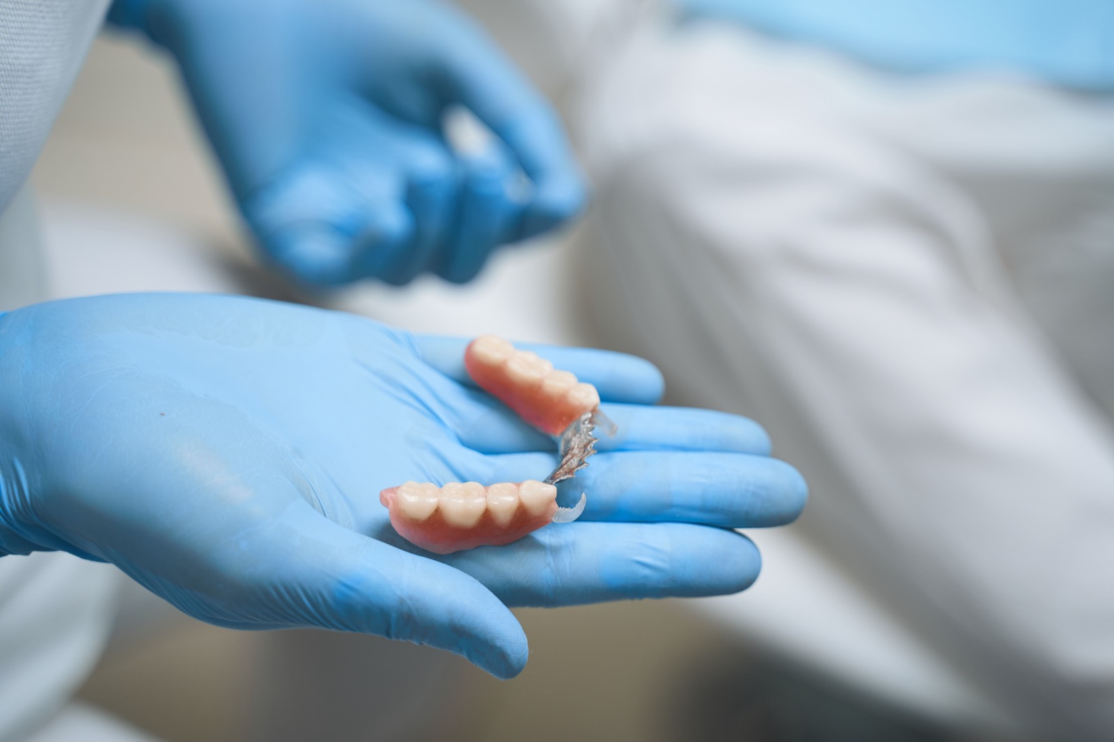 Dental specialist is standing in rubber gloves and holding tools for giving new teeth to patient