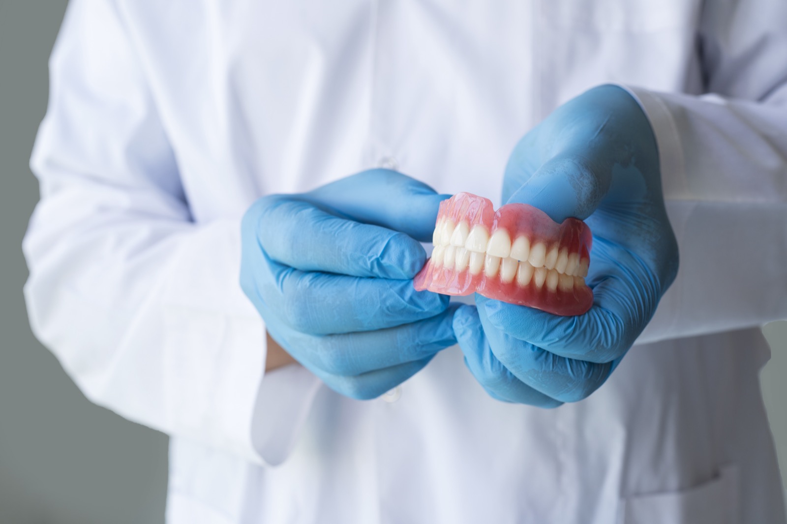 Male dentist holding a teeth denture. False teeth