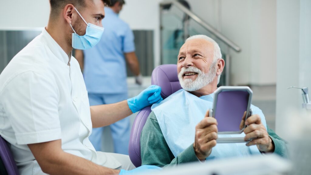 Satisfied senior man communicating with his dentist after dental procedure at denturist office.